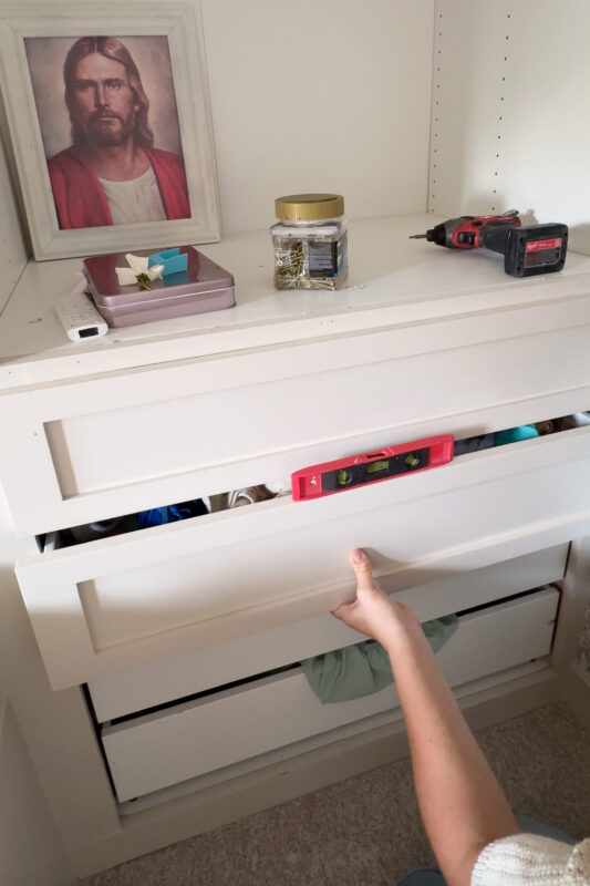 Installing a drawer front onto a drawer in a built-in bunk bed.